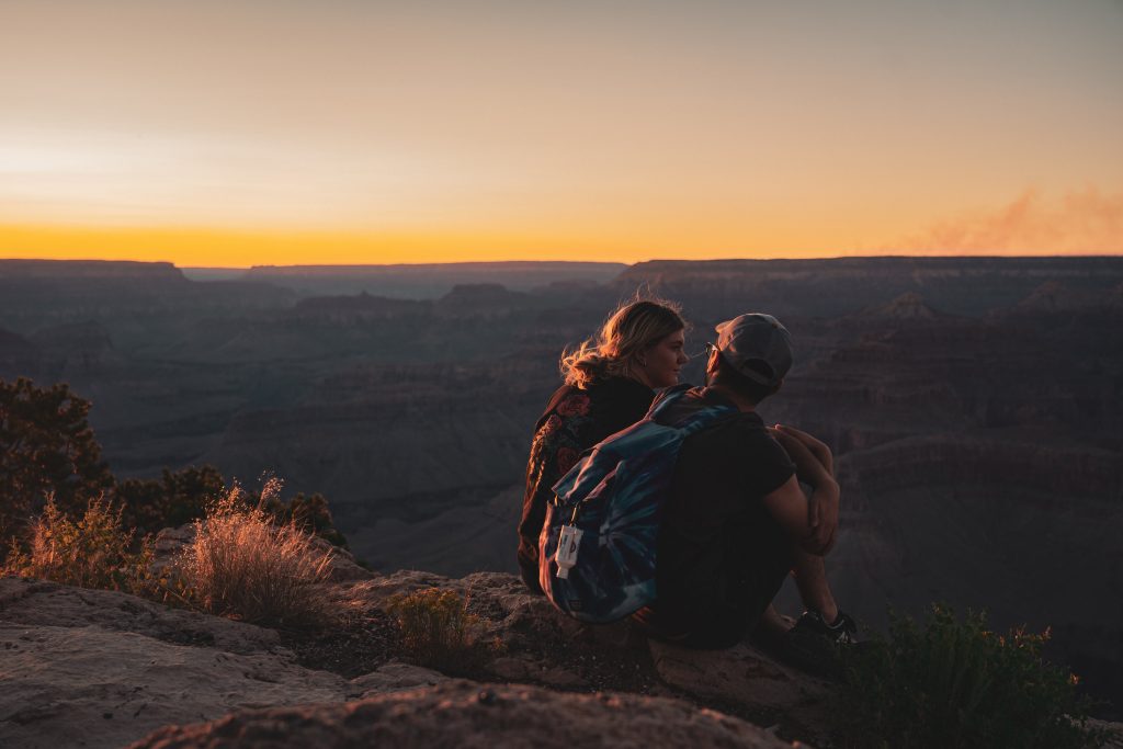 man and woman sitting near canyon 