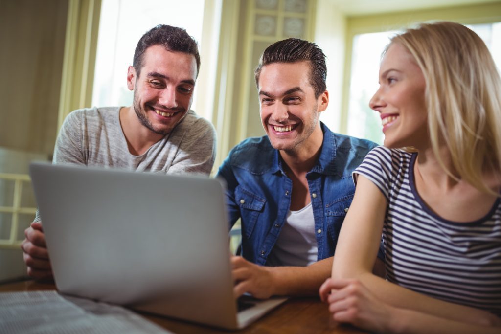 Friends sitting at table and using laptop in cafe